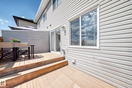 Spacious outdoor deck with natural wood planks, featuring a privacy wall with horizontal siding - 93 Richmond Link, Fort Saskatchewan, AB 