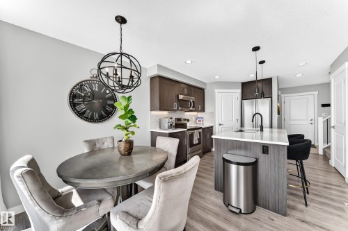 Open-concept kitchen and dining area featuring warm wood-finish flooring - 93 Richmond Link, Fort Saskatchewan, AB 