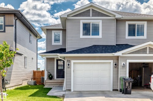 Two-story residence featuring light gray horizontal siding and decorative shingle accents - 93 Richmond Link, Fort Saskatchewan, AB 