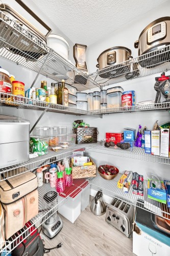Corner pantry featuring extensive wire shelving, light wood-finish flooring, and white walls - 93 Richmond Link, Fort Saskatchewan, AB 