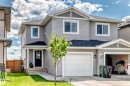 Gray siding exterior with white trim, featuring a single-car garage with a white door - 93 Richmond Link, Fort Saskatchewan, AB 