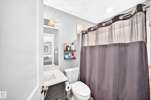 Bathroom featuring a vanity with an integrated sink, a built-in mirror, and a wall-mounted light fixture - 93 Richmond Link, Fort Saskatchewan, AB 