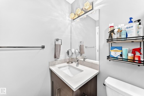 Bathroom vanity with integrated sink, wood-finish cabinetry, and light-toned countertop - 93 Richmond Link, Fort Saskatchewan, AB 