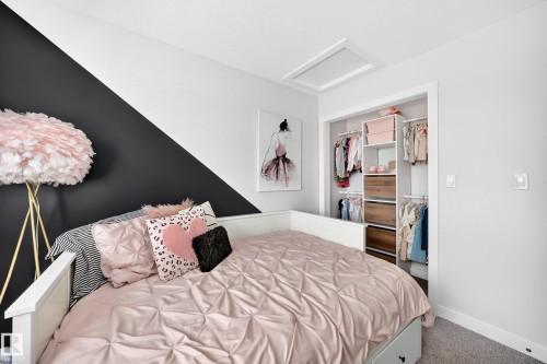 Room featuring a built-in bed frame with storage drawers, a custom closet organization system with shelving and hanging rods, and a two-tone wall with a diagonal design - 93 Richmond Link, Fort Saskatchewan, AB 