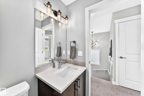 Bathroom vanity featuring a vessel sink, white countertop, dark wood-finish cabinetry, and chrome fixtures - 93 Richmond Link, Fort Saskatchewan, AB 