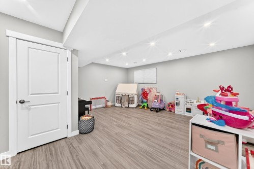 Finished interior space featuring wood-finish flooring, recessed ceiling lighting, light gray painted walls, and white trim - 93 Richmond Link, Fort Saskatchewan, AB 