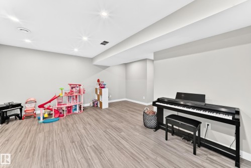 Spacious room featuring wood-finish flooring, light grey painted walls, and recessed lighting - 93 Richmond Link, Fort Saskatchewan, AB 