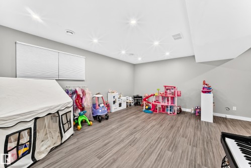 Spacious room featuring wood-finish flooring, recessed lighting, and neutral wall tones - 93 Richmond Link, Fort Saskatchewan, AB 