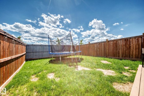 Private backyard featuring a manicured lawn, wood fencing, and a multi-level wood deck - 93 Richmond Link, Fort Saskatchewan, AB 