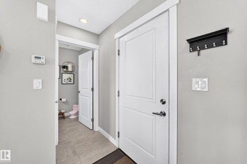 Interior entryway featuring a white paneled door with brushed nickel hardware, light gray wall paint, and recessed ceiling lighting - 93 Richmond Link, Fort Saskatchewan, AB 