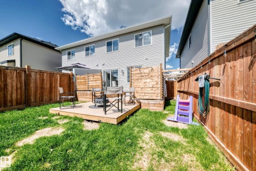 Private backyard featuring a wooden deck, sliding patio door, and full perimeter wood fencing - 93 Richmond Link, Fort Saskatchewan, AB 