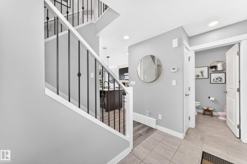 Modern staircase with white handrails and black metal spindles - 93 Richmond Link, Fort Saskatchewan, AB 