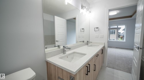 Dual vanity with integrated sinks, light-toned wood-finish cabinetry, and contemporary black hardware - 3708 40 Ave, Beaumont, AB 