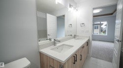 Dual vanity with integrated sinks, light-toned wood-finish cabinetry, and contemporary black hardware - 