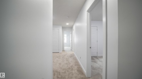 Hallway featuring light-toned carpet, recessed lighting, white walls, and multiple paneled doors - 3708 40 Ave, Beaumont, AB 