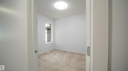 Carpeted interior room featuring a single window with blinds, baseboard trim, and a ceiling-mounted light fixture - 