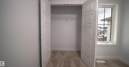 Bedroom featuring a spacious closet with bifold doors, wire shelving, and neutral carpeting - 3708 40 Ave, Beaumont, AB 