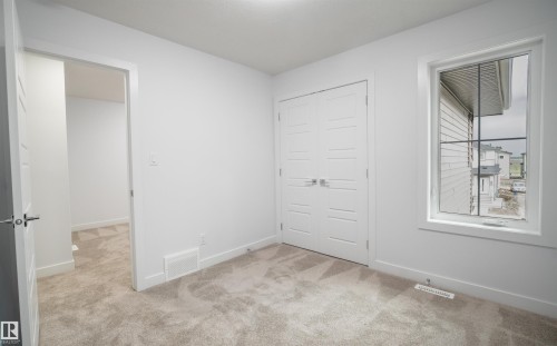 Spacious room featuring neutral carpeting, white trim, and a double-door closet with modern hardware - 3708 40 Ave, Beaumont, AB 