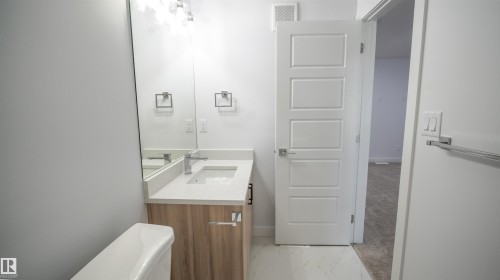 Modern bathroom vanity with wood-finish cabinetry, white countertop, and an integrated rectangular sink - 3708 40 Ave, Beaumont, AB 