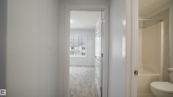 Hallway featuring white walls and trim - 