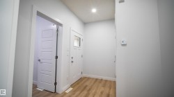 Entryway featuring wood-finish flooring, recessed lighting, and a white paneled door with frosted glass insert - 