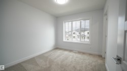Spacious room featuring neutral carpeting, white painted walls, a large multi-pane window, and a flush-mount ceiling light fixture - 