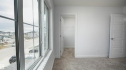 Bright interior space featuring a large multipane window, plush grey carpeting, white painted walls, and a modern five-panel interior door - 