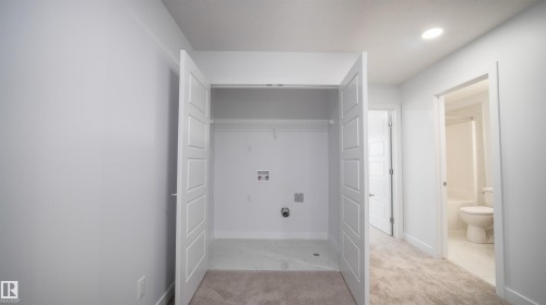 Dedicated laundry closet with hookups, bi-fold doors, and overhead shelving - 3708 40 Ave, Beaumont, AB 