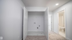 Dedicated laundry closet with hookups, bi-fold doors, and overhead shelving - 