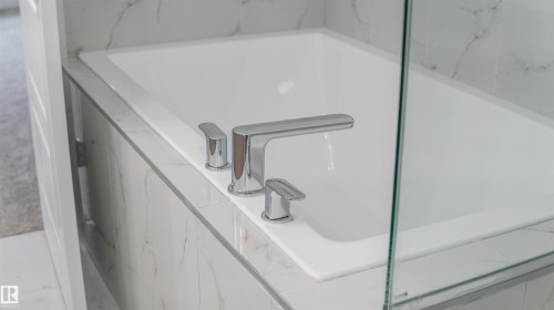 Built-in soaking tub featuring chrome fixtures, full tile surround, and a glass partition - 3708 40 Ave, Beaumont, AB 
