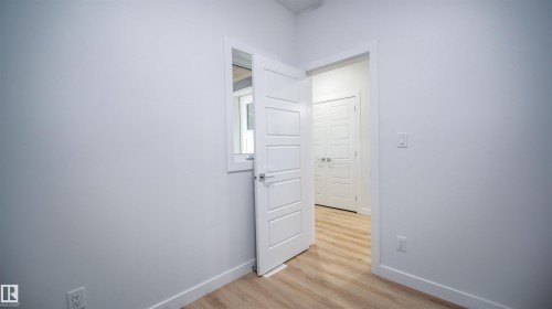 Light wood-finish flooring throughout, featuring crisp white walls and baseboards - 3708 40 Ave, Beaumont, AB 