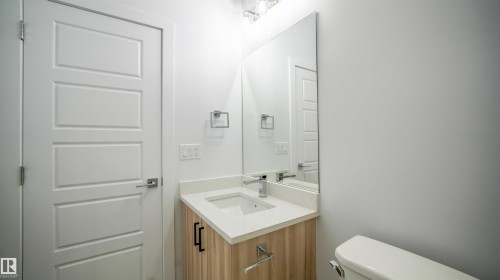 Modern bathroom vanity featuring a light wood-finish cabinet with black hardware, a rectangular undermount sink, and a light-toned countertop - 3708 40 Ave, Beaumont, AB 