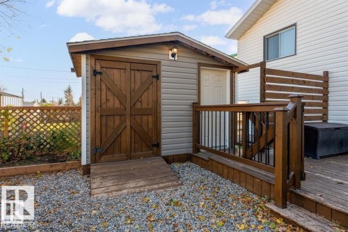 Exterior shed featuring horizontal siding and barn-style wooden doors with black hardware - 1112 13 Avenue, Cold Lake, AB - Outdoor With Deck Patio Veranda With Exterior