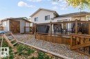 Rear exterior featuring a spacious wooden deck with black metal railings, a gravel patio area, a shed with double wooden doors, and white siding - 1112 13 Avenue, Cold Lake, AB  - Outdoor With Deck Patio Veranda With Exterior 