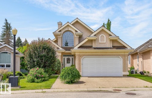 Stucco exterior with a pitched roofline, featuring an arched window, a two-car garage, and a concrete driveway - 6 Prestige Point Nw, Edmonton, AB 
