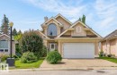 Stucco exterior with a pitched roofline, featuring an arched window, a two-car garage, and a concrete driveway - 6 Prestige Point Nw, Edmonton, AB 