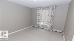 Room featuring light neutral-toned walls, beige carpeting, and white baseboards - 