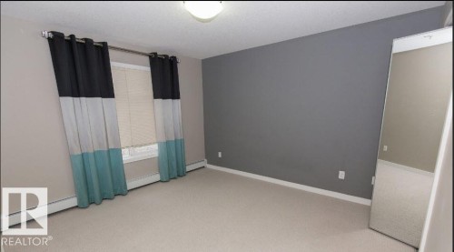 Spacious room featuring neutral carpeting, a window with horizontal blinds, and a neutral wall color - #141 11505 Ellerslie Rd, Edmonton, AB 