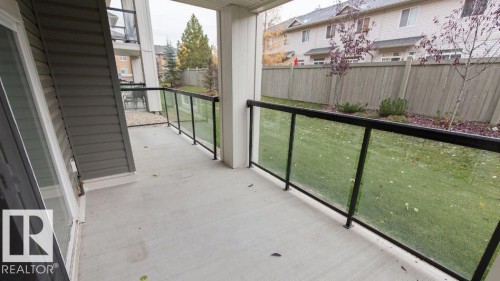 Ground-level concrete patio featuring a glass and metal railing system - #141 11505 Ellerslie Rd, Edmonton, AB 