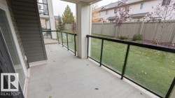 Ground-level concrete patio featuring a glass and metal railing system - 