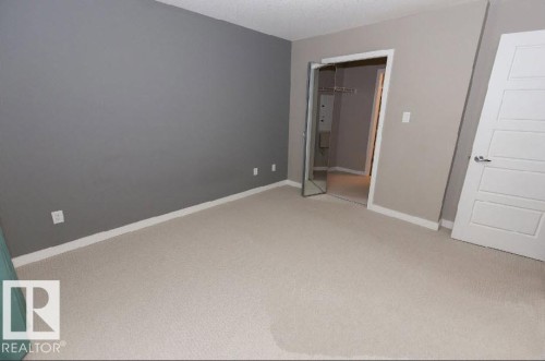 Carpeted room featuring a neutral color palette, contemporary white trim, and a full-length mirrored closet door - #141 11505 Ellerslie Rd, Edmonton, AB 