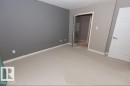 Carpeted room featuring a neutral color palette, contemporary white trim, and a full-length mirrored closet door - #141 11505 Ellerslie Rd, Edmonton, AB 