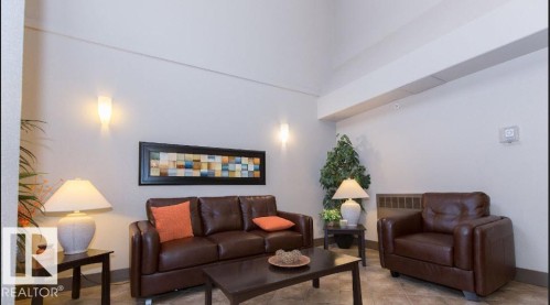Spacious common area featuring high ceilings, wall-mounted sconces, and neutral wall tones - #141 11505 Ellerslie Rd, Edmonton, AB 