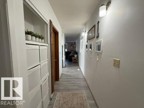 Hallway featuring light wood-finish flooring, white painted walls, and built-in closet shelving with storage cubbies - 4917 45 Avenue, Vegreville, AB - Indoor Photo Showing Other Room