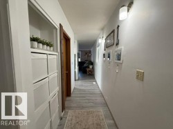 Hallway featuring light wood-finish flooring, white painted walls, and built-in closet shelving with storage cubbies - 