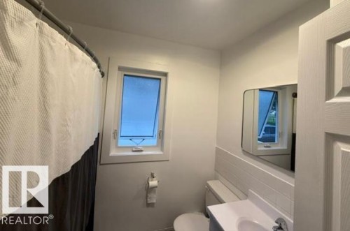 Bathroom featuring a casement window, a rectangular vanity mirror, and a white vanity with an integrated sink - 4917 45 Avenue, Vegreville, AB - Indoor Photo Showing Bathroom