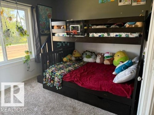 Built-in bunk bed system featuring a dark wood-finish frame, integrated storage drawers, and an attached ladder - 4917 45 Avenue, Vegreville, AB - Indoor Photo Showing Bedroom
