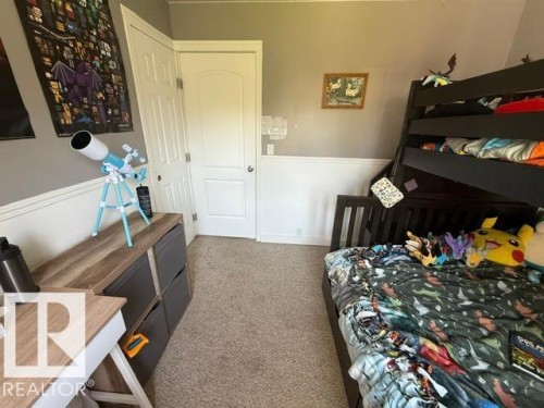 Carpeted room featuring a built-in bunk bed, white wainscoting, and a paneled interior door - 4917 45 Avenue, Vegreville, AB - Indoor