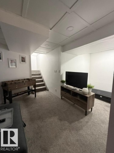 Carpeted entertainment area featuring a built-in media console, recessed lighting, and a paneled ceiling with decorative trim - 4917 45 Avenue, Vegreville, AB - Indoor