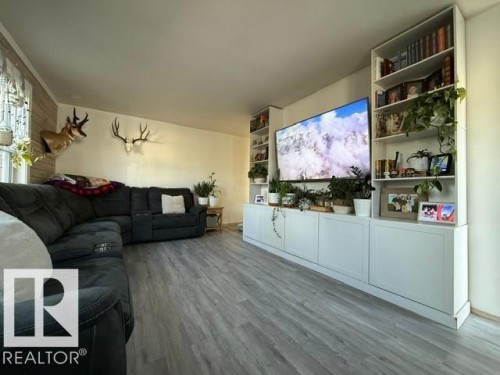 Spacious living area featuring light wood-finish flooring, a bright window, and a built-in media center with integrated shelving - 4917 45 Avenue, Vegreville, AB - Indoor